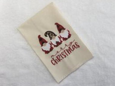 This teal towel is adorned with appliqued gnomes with Merry Christmas embroidered underneath the three gnomes